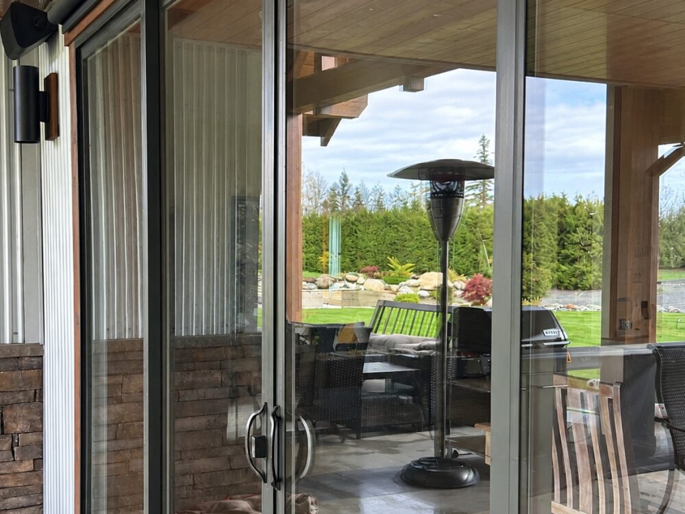 The same patio doors after cleaning, the garden and sky behind them sharp and bright
