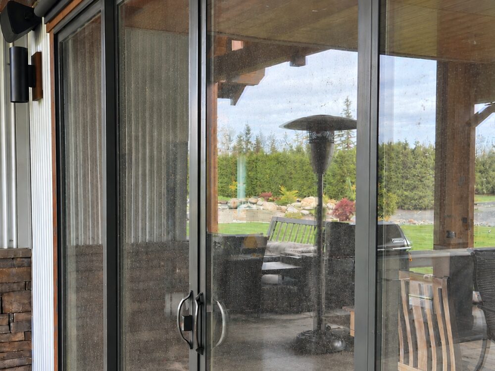 Patio door glass covered in water spots and grime, hazing everything behind it