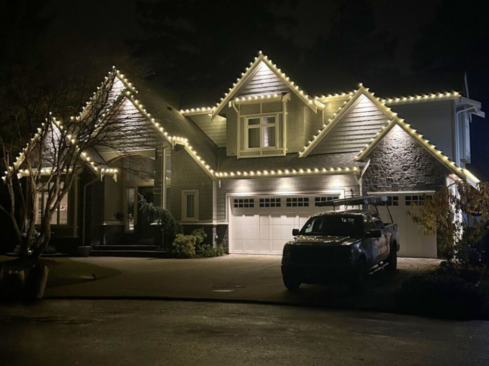 A Delta home at night with warm white C9 lights tracing every roofline, dormer and peak
