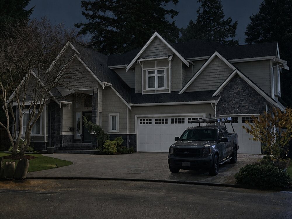 The same home on the same evening before the lights were switched on, rooflines dark